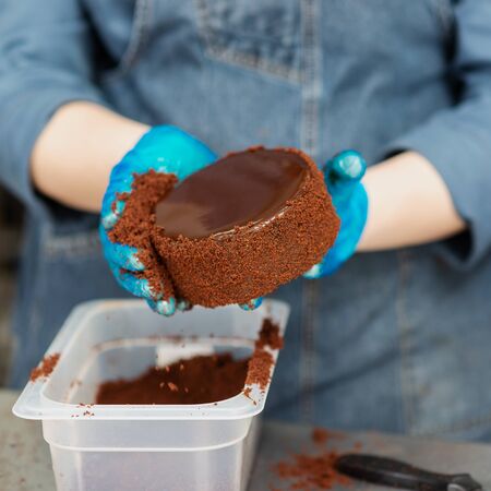 Hands of a confectioner with gloves make a chocolate cakeの写真素材