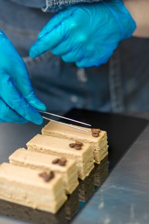 Hands of a confectioner with gloves make a chocolate cakeの写真素材