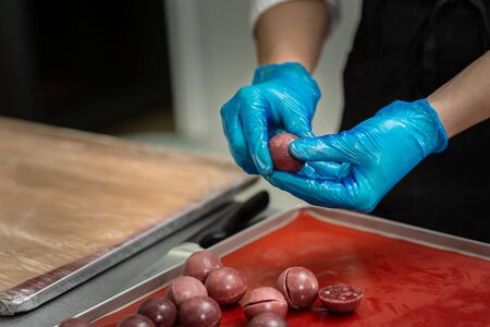Gloved hands of confectioner make chocolate candiesの写真素材