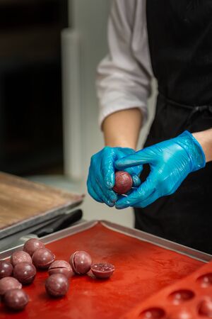 Gloved hands of confectioner make chocolate candiesの写真素材