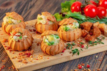 Profiteroles with vegetable filling, tomatoes and herbs on a wooden backgroundの写真素材