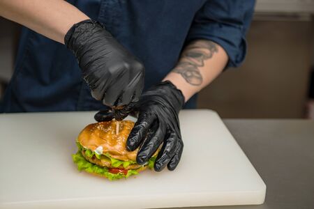chef makes a burger with meat and herbsの写真素材