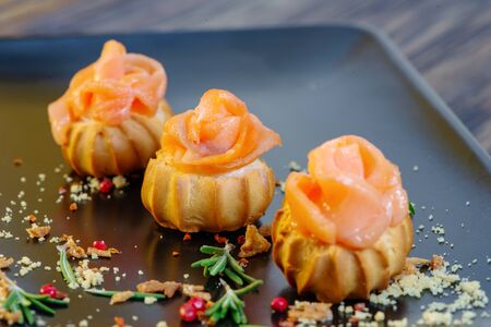 Profiteroles with red fish on a black background