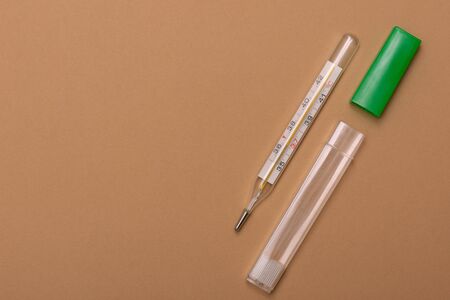 Mercury thermometer on a brown background, with copy space, top view.