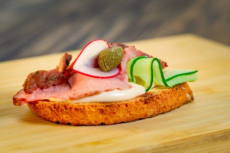 Tasty sandwiches with ham, cucumber, seasonings on a gray table, close upの写真素材