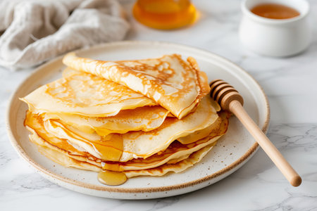 Delicious pancakes with honey or maple syrup. Homemade pancakes and sweet syrup on white plate isolated. High quality photoの写真素材