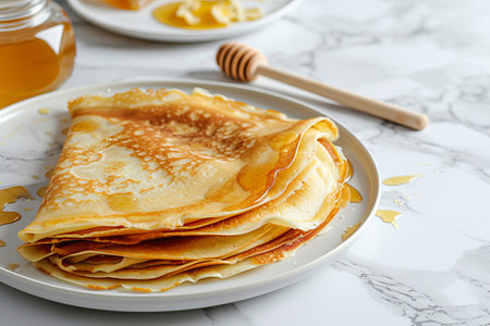 Delicious pancakes with honey or maple syrup. Homemade pancakes and sweet syrup on white plate isolated. High quality photoの写真素材