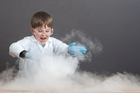 The schoolboy is conducting an experiment in the laboratory. Sublimation of dry ice, emotional moment. Large protective goggles. School education, physics.の写真素材