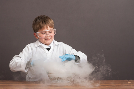 The schoolboy is conducting an experiment in the laboratory. Sublimation of dry ice, emotional moment. Large protective goggles. School education, physics.の写真素材