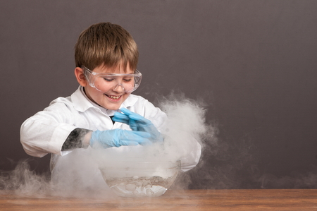 The schoolboy is conducting an experiment in the laboratory. Sublimation of dry ice, emotional moment. Large protective goggles. School education, physics.の写真素材