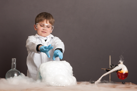 The schoolboy is conducting an experiment in the laboratory. Sublimation of dry ice, emotional moment. Large protective goggles. School education, physics.の写真素材