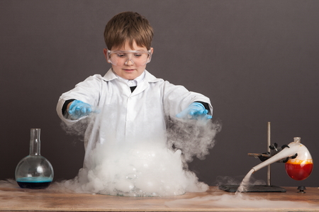 The schoolboy is conducting an experiment in the laboratory. Sublimation of dry ice, emotional moment. Large protective goggles. School education, physics.の写真素材