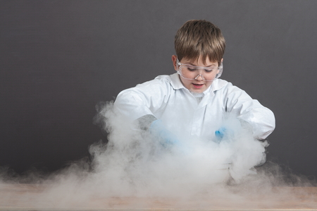 The schoolboy is conducting an experiment in the laboratory. Sublimation of dry ice, emotional moment. Large protective goggles. School education, physics.の写真素材