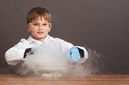 The schoolboy is conducting an experiment in the laboratory. Sublimation of dry ice, emotional moment. Large protective goggles. School education, physics.の写真素材