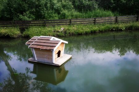 Small wooden house on water with reflectionの写真素材