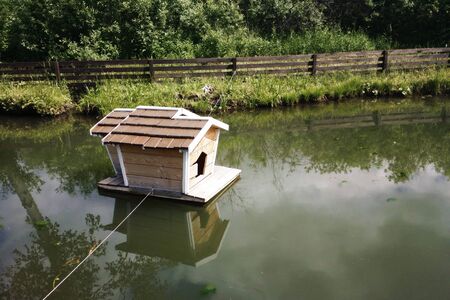 Small wooden house on water with reflectionの写真素材