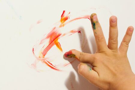 Smeared child's finger draws doodles with red paint on white sheet. Selective focus.の写真素材