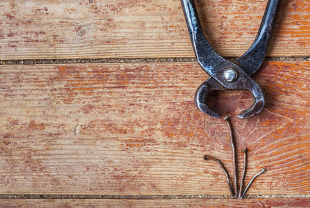 Pliers and old bent nails on the background of the wooden floor - visibility of workの写真素材