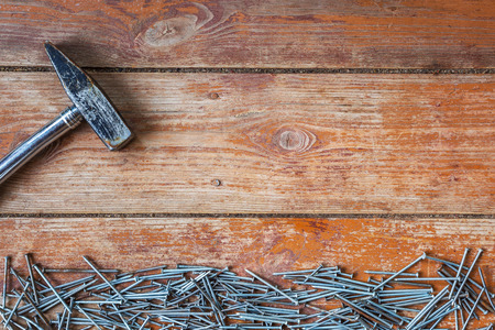 A pile of nails laid out in the bottom of the picture and old hammer on the background of the old wooden floorの写真素材