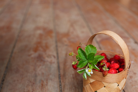 Basket with ripe berries strawberries on the background of the wooden floorの写真素材
