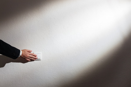 Man's hand turns off the lightの写真素材
