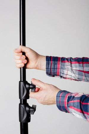 photographer adjusts the height of stand for lighting equipmentの写真素材