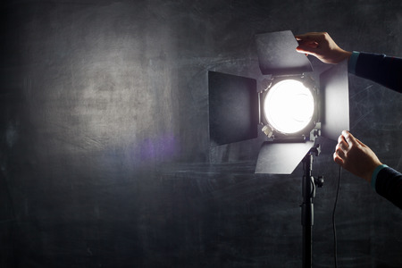 Photographer adjusts lighting equipment on a background of chalkboard