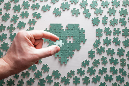 Silhouette of the heart made up of pieces of puzzles, with a hole in the middleの写真素材