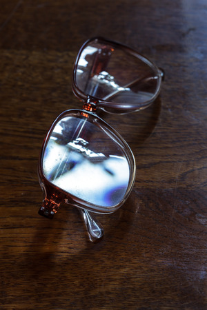 Old pensioner glasses on lacquered wooden surface. Blurred vision of old ageの写真素材
