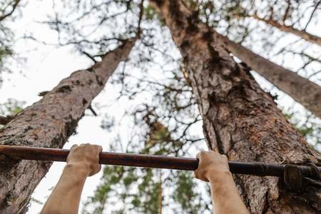 exercising, training and lifestyle concept. young man doing pull ups on horizontal bar at the wood...