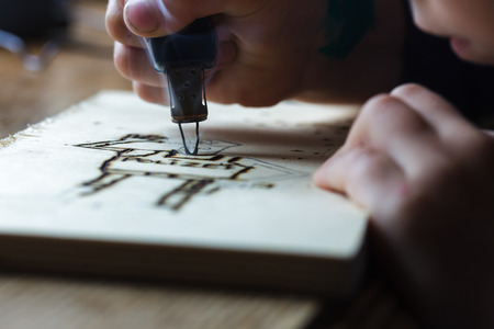interesting hobby for children. Burning drawing on a wooden surfaceの写真素材