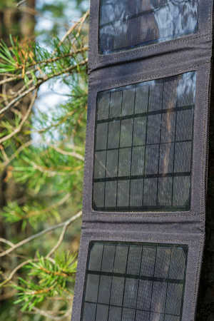 Portable solar panels are hanging on a tree and accumulate energy