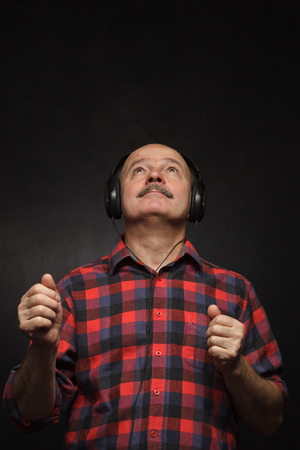 Elderly man with headphones listening to music with pleasure.の写真素材