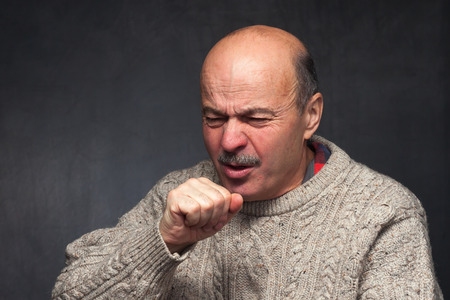 Elderly man is ill from colds or pneumonia. elderly man in a sweater and a woolen scarf strongly...