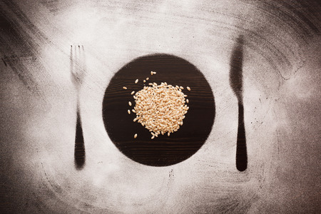 pearl barley in plate, knife and fork silhouettes.の写真素材