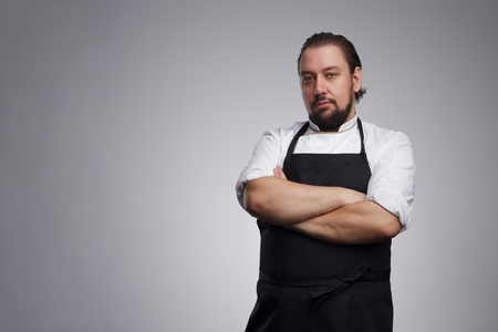 Chef cook in white uniform and a black apron, he folded his arms and looking confidently forwardの写真素材