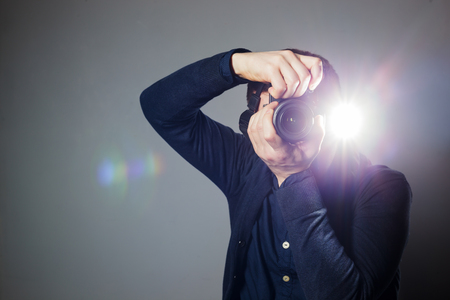 Young man takes a picture on a camera with built-in flash. Bright light for illumination of the frame.の写真素材