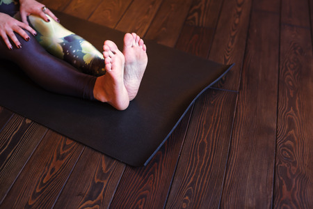girl sits on a mat with straight legs doing yogaの写真素材