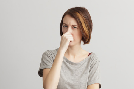 Disgusting smelling. Girl frowns with displeasureの写真素材