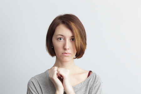 Timid and girl shyly looking ahead, clenched hands into fistsの写真素材