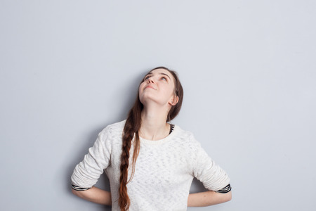 Girl with long hair sitting in jeans and looking upの写真素材