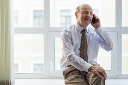 elderly businessman conducts informal talks on the phoneの写真素材