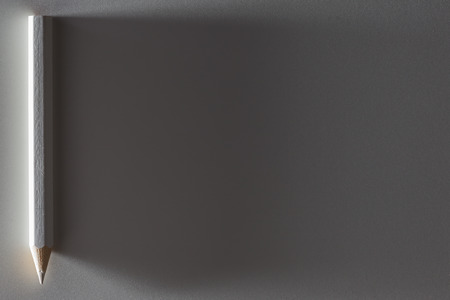 White pencil on white paper with deep shadowの写真素材