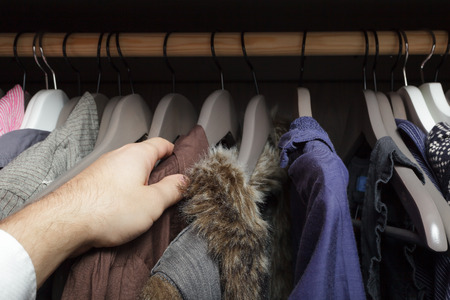 Man chooses clothes, rummaging in the cupboardの写真素材
