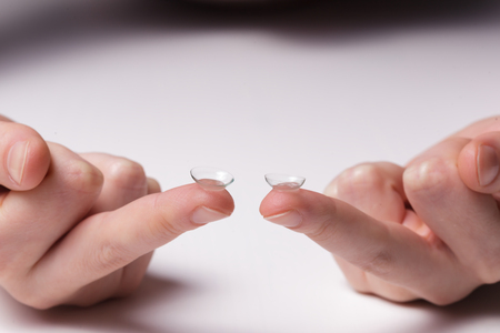 Girl holds a contact lens on  fingersの写真素材
