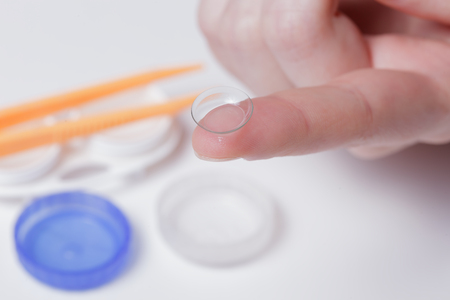 Girl holds a contact lens on the index fingerの写真素材