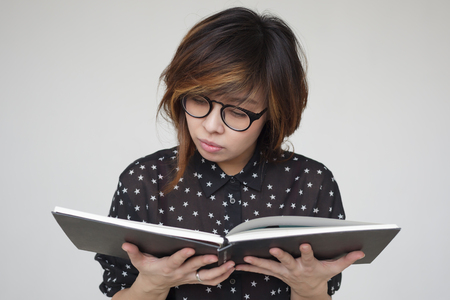 Asian girl in glasses reads the book carefully.の写真素材