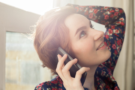 Beautiful girl with short hair  dreamy with enthusiasm talking on the phoneの写真素材