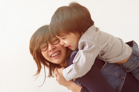 Japanese mother hugs her son, they laugh and smile. Warm family relations.の写真素材