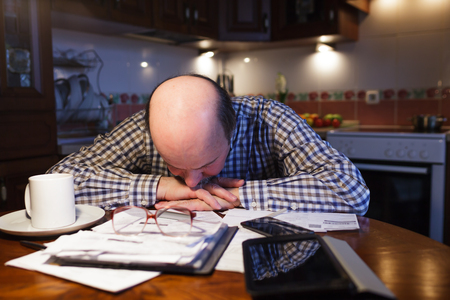 A man tiredly considers the family budget. Lack of money in the crisis.の写真素材